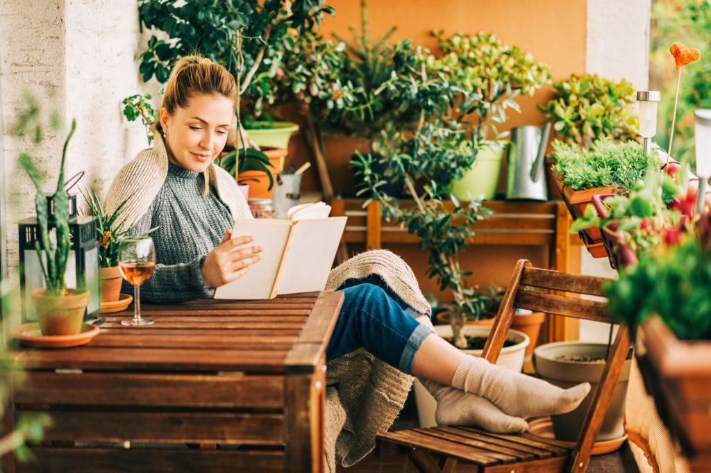 jeune femme lisant un livre sur une terrasse arborée
